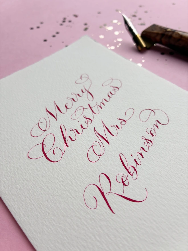 Calligraphy Christmas card close up of personalisation in red ink with calligraphy pen 