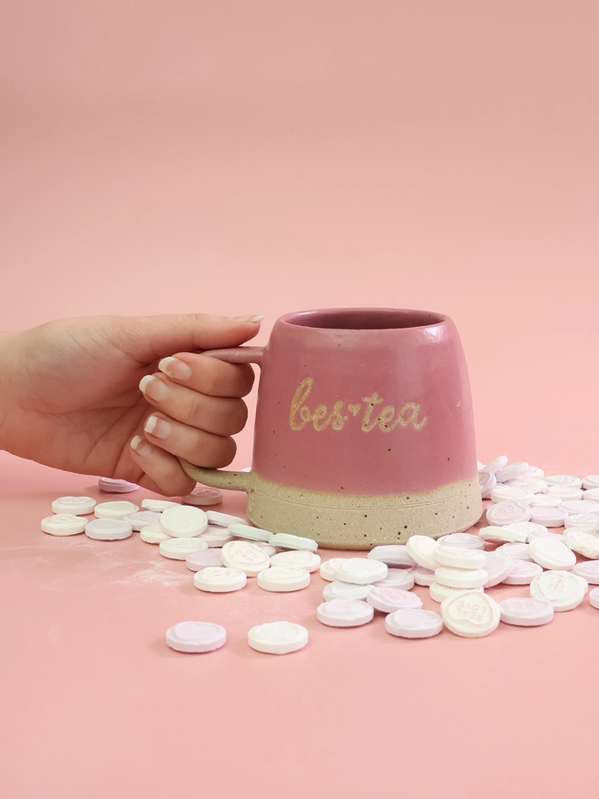 a bestea saying on the front of a hot pink handmade mug surrounded by love heart sweets