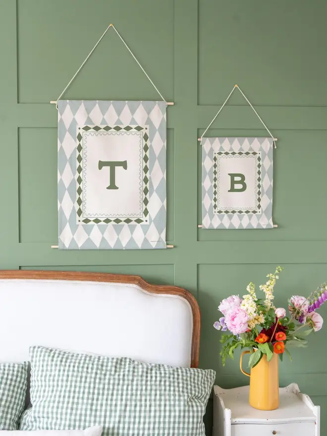 Harlequin Initial Fabric Banner, blue mini and midi next to each other against a green wall. 