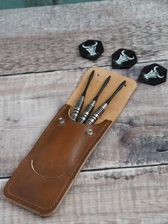 Personalised leather darts sleeve. A handmade tan brown case with 3 darts and 3 flights spreading out from within, showing what it holds.