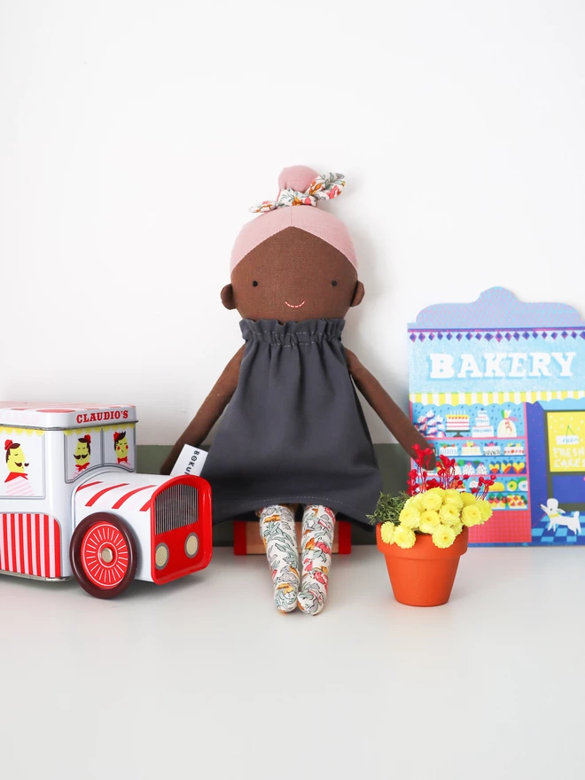 black girl doll with pink hair and liberty print tights and bow