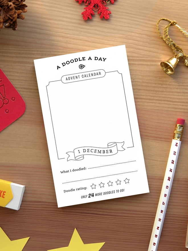 Odd Goose Creative Advent Calendar Doodle A Day notepad lifestyle shot seen top down with festive ornaments and a foil printed advent calendar pencil