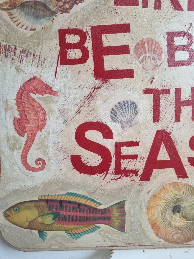 An art panel made from a collage of antique botanical sea creature images in a limited palette of blues, reds browns and pinks on a cream textured background with text in red that reads 'oh I do like to be beside the seaside'.