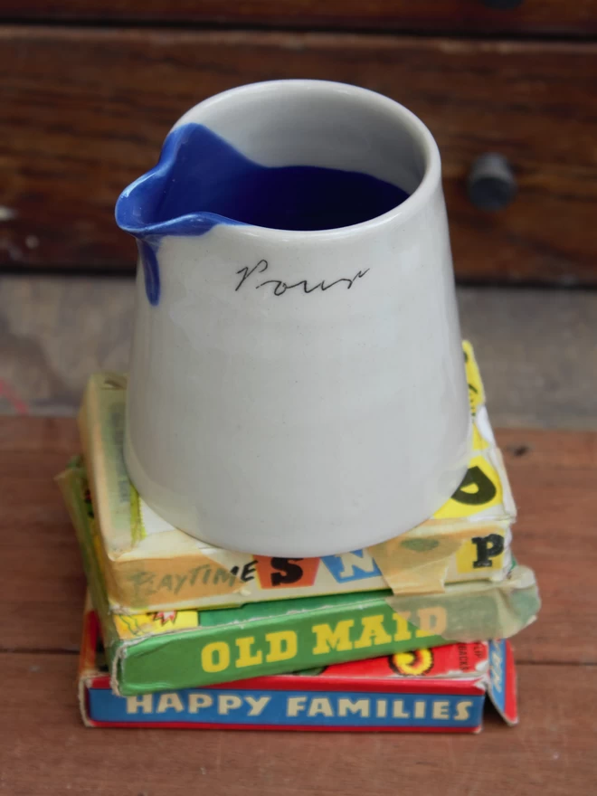 mini pouring jug on a stack of old playing cards