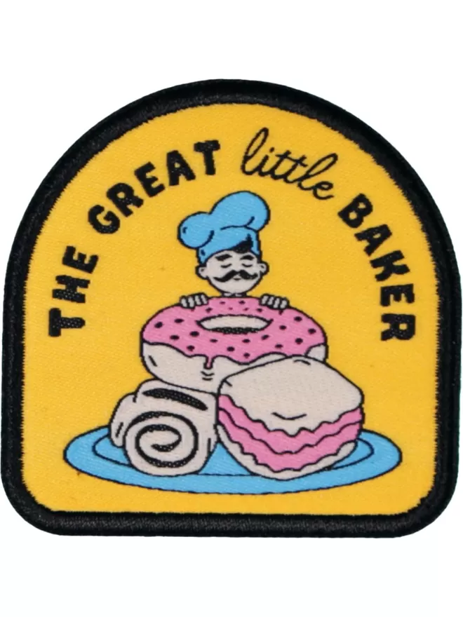 On a yellow background a baker with a blue hat peers over large treats on a blue plate. 'The great little baker' is stitched above.