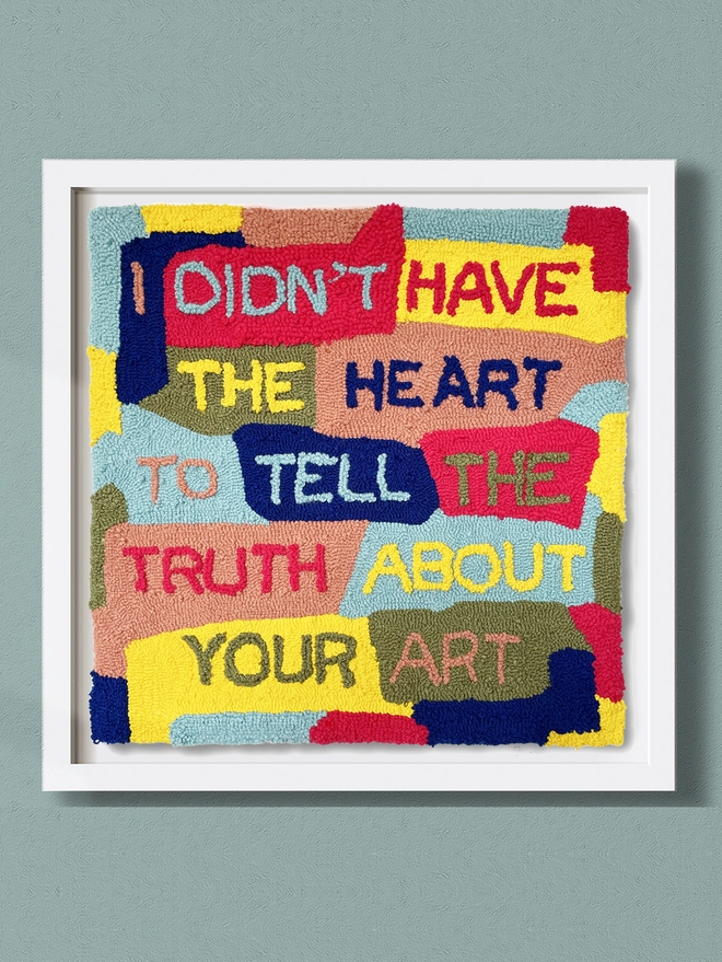 Typographic textile art 'I didn't have the heart to tell the truth about your art' in primary colours on patchwork background