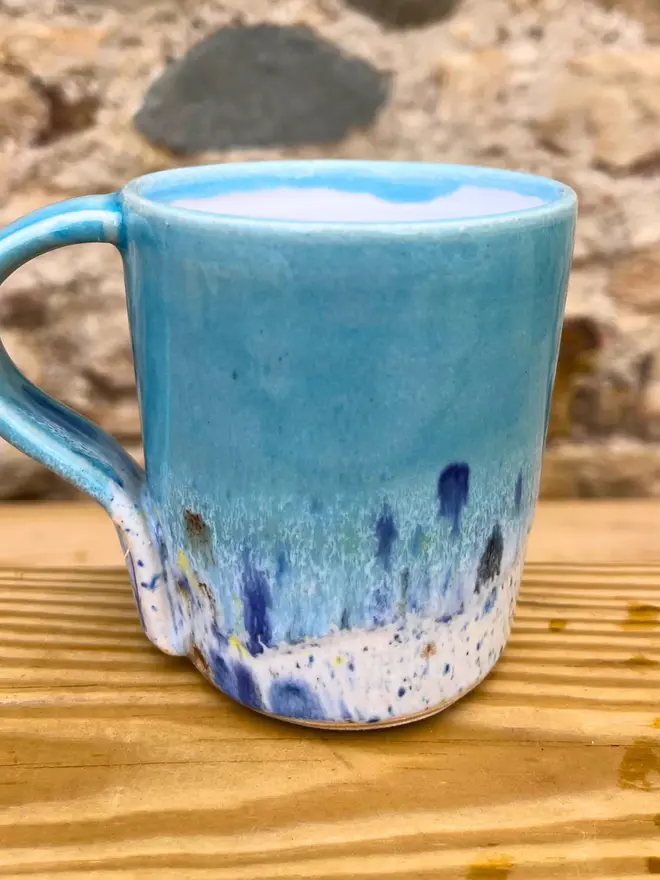 Shoreline Standard Mug, a colourful mug placed on a wooden surface. 