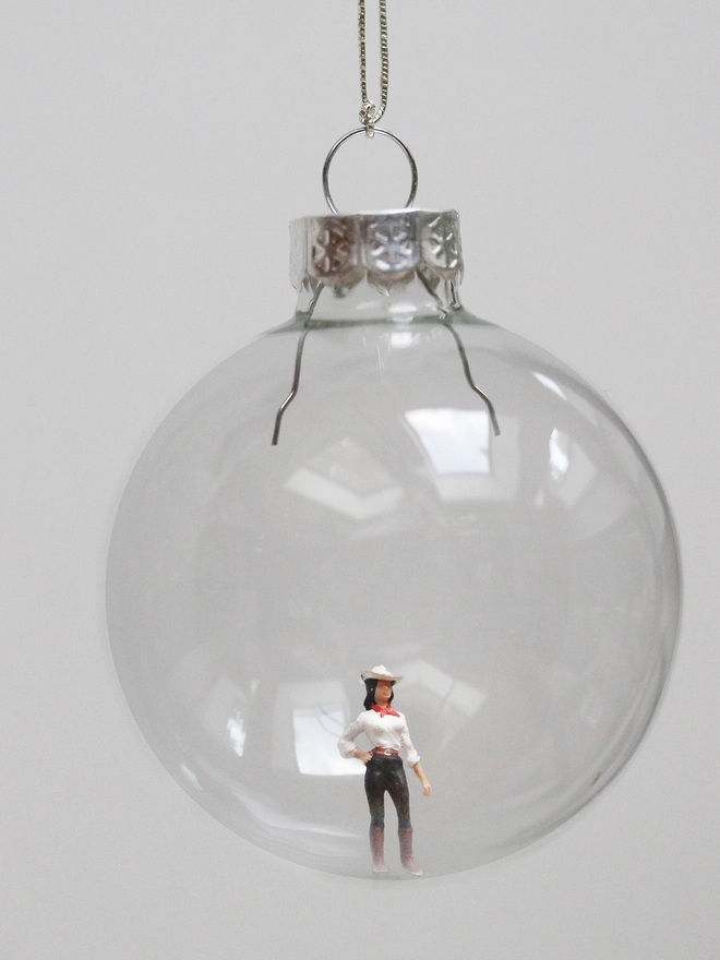 miniature cowgirl figure in a glass christmas bauble