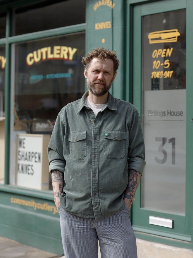 Man in green jacket standing in front of shop