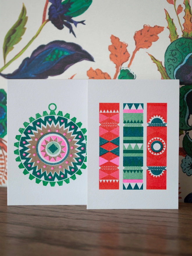 Two retro mini Christmas cards with a modern twist. A scandi style festive bauble design and a nordic influenced little group of crackers, both designs are printed in festive vibrant inks