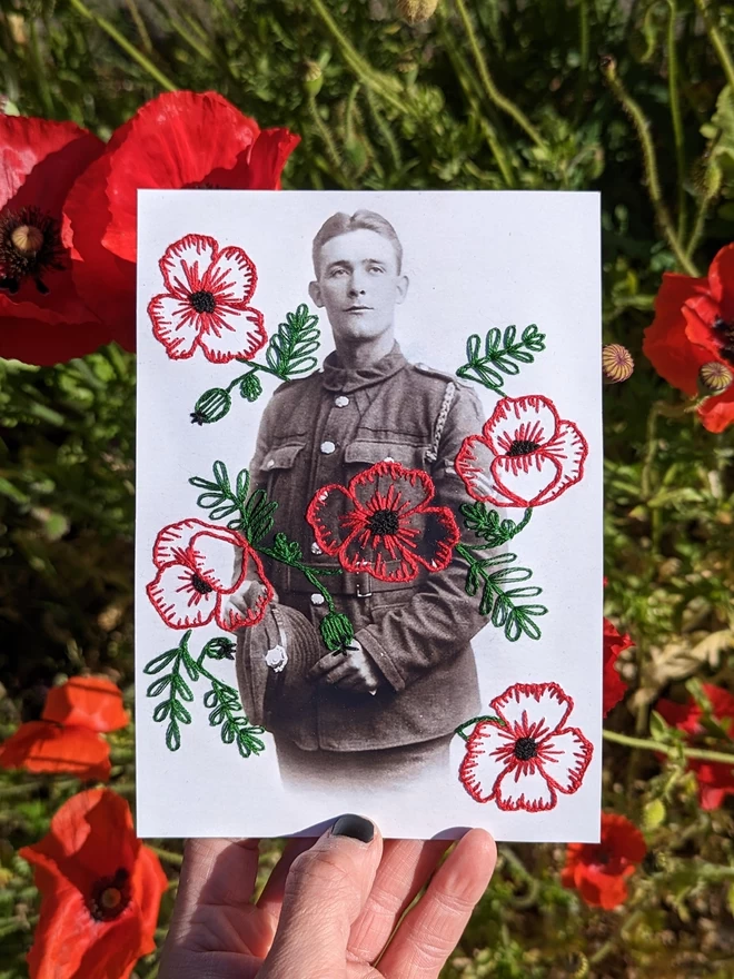 Photo of a man with hand embroidered poppies surrounding him, held against a field of poppies