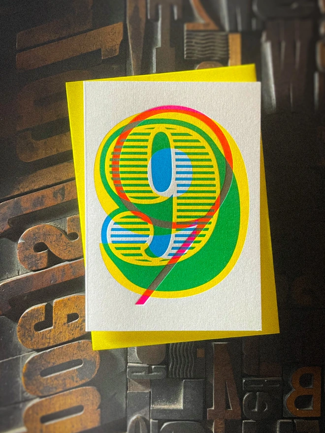 Handmade letterpress 9th birthday card featuring bold overlapping numerals printed in vibrant fluorescent cyan, magenta and yellow inks. Each card is individually hand printed using traditional letterpress techniques on luxury paper stock, creating a beautifully tactile finish with a deep impression and rich layered colours inspired by the CMYK printing process. Printed on a traditional letterpress from 1915. A wonderful artisan printed birthday card.