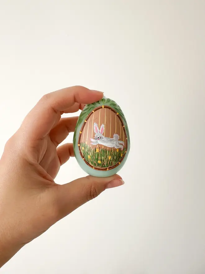 Hand Painted Easter Egg Candle Bunny, a green Easter egg candle held by a woman against a plain backdrop. 