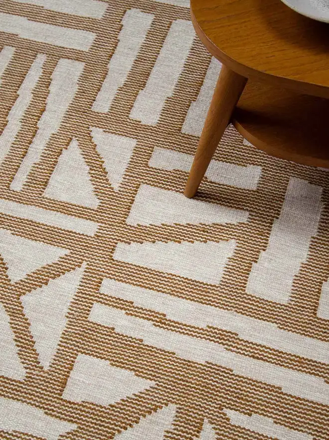 Tudor Flatweave Rug, a colourful rug in a living room. It is surrounded by other household items. 