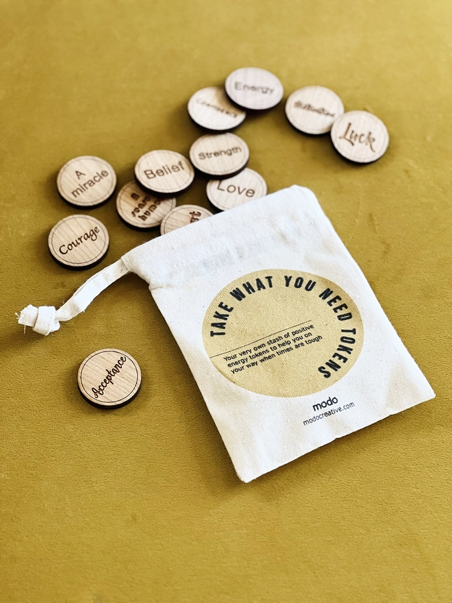 A small drawstring bag with "Take what you need tokens" printed on. 12 tokens spilled out of the bag 