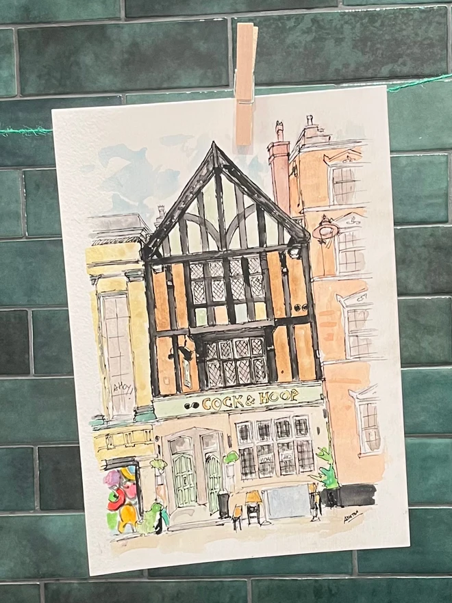 watercolour painting of a Pub, hanging from a clothesline in front of green tile