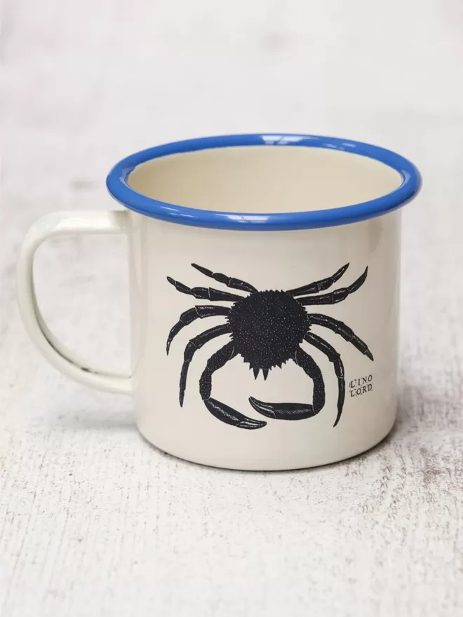 Picture of a Cream Enamel Mug with a Blue Rim with a Spider Crab design etched onto it, taken from an original Lino Print