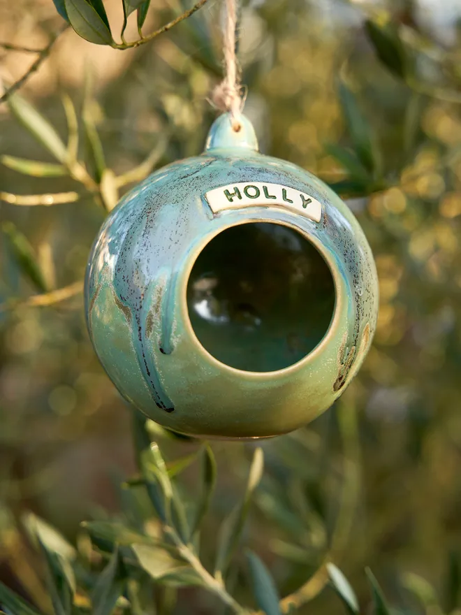 Personalised Water Moss Globe hanging from a tree personalised with the name 'Holly'