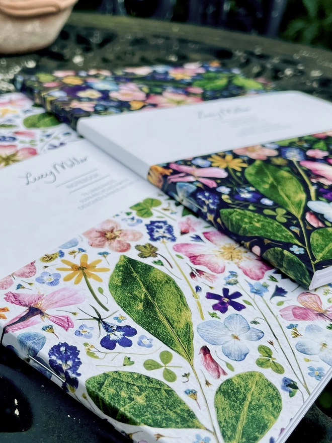 Light and Dark Notebooks with Design of Pressed Flowers and Leaves, Stapled Spines on Garden Table