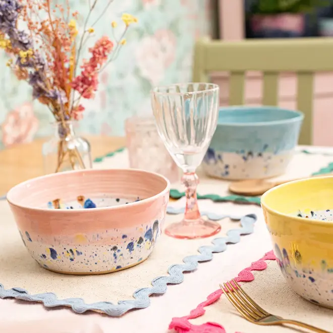 Shoreline Ramen Bowl, a group of colourful ramen bowls placed on a table setting accompanied by napkins, glasses and other dining items. 