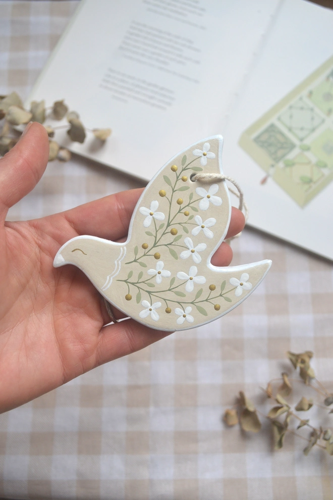 beige ceramic hanging bird ornament with white floral design