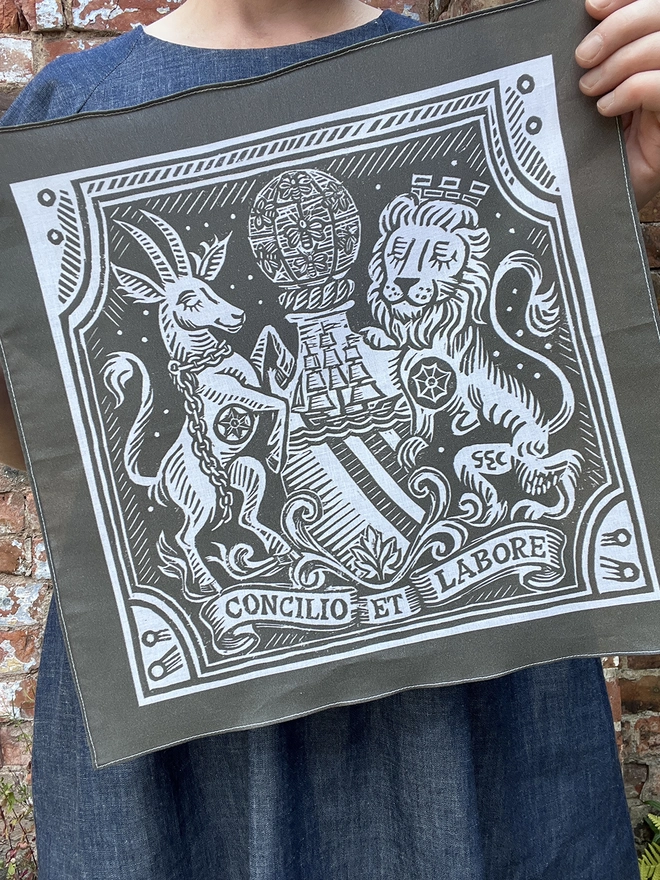 A Mr.PS grey Manchester Coat of Arms printed cotton square being held