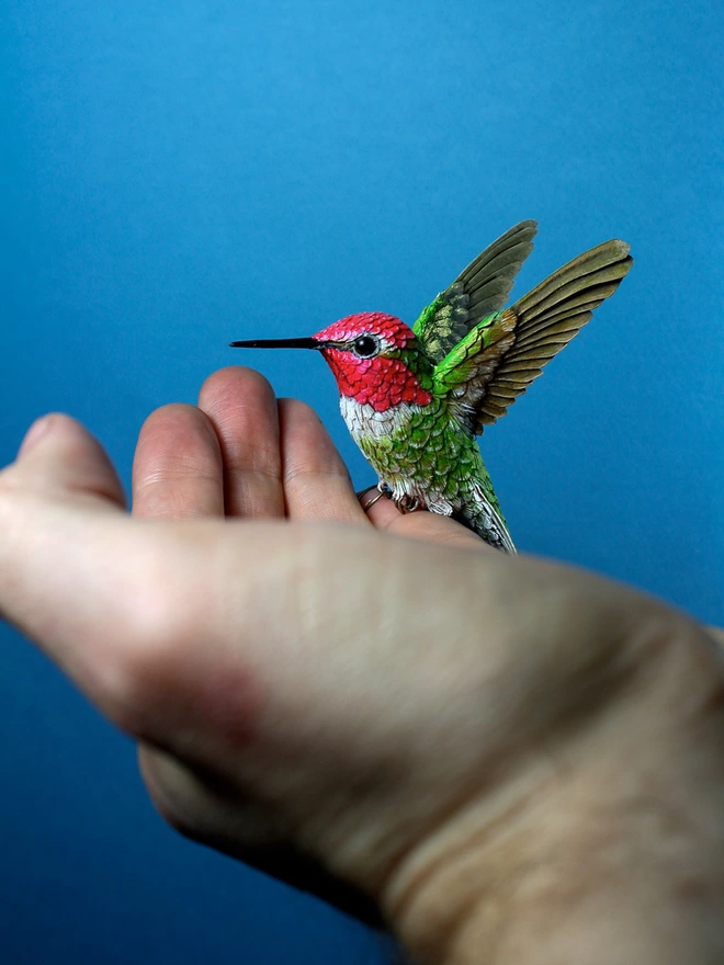 Paper Annas hummingbird sculpture on artists hand