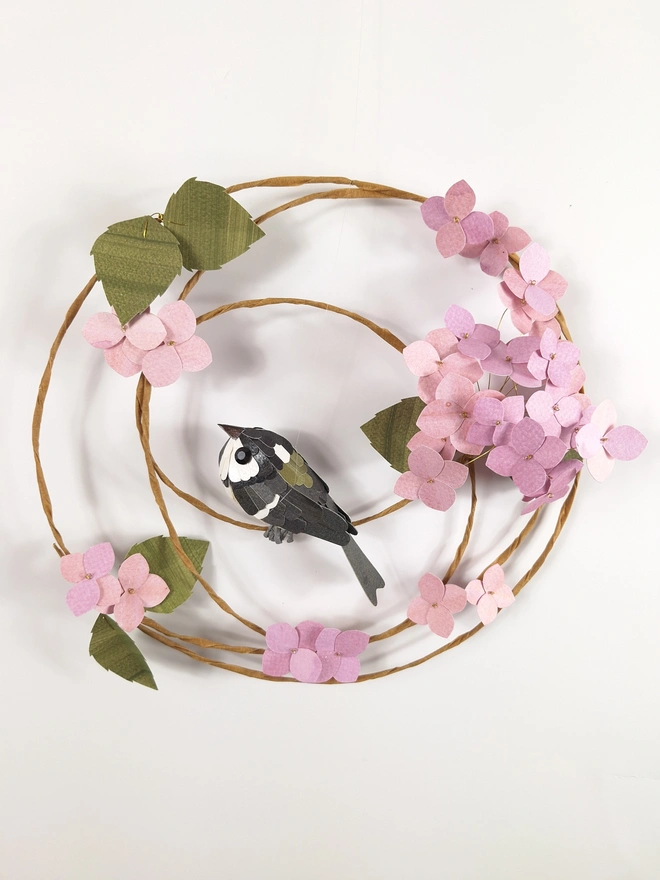 Coal tit bird sculpture, perched on a spring wreath of pink hydrangea