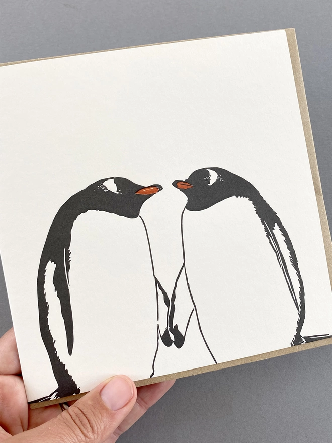 A hand holding the Gentoo kiss big card that is letterpress printed and designed in the UK