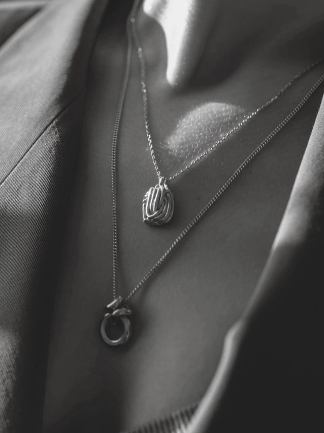 a black and white photo of two chunky layered silver pendants