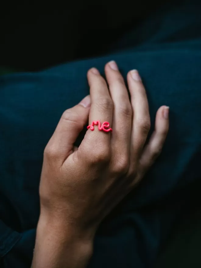 This Is 'Me' Statement Ring in pink seen on a hand.