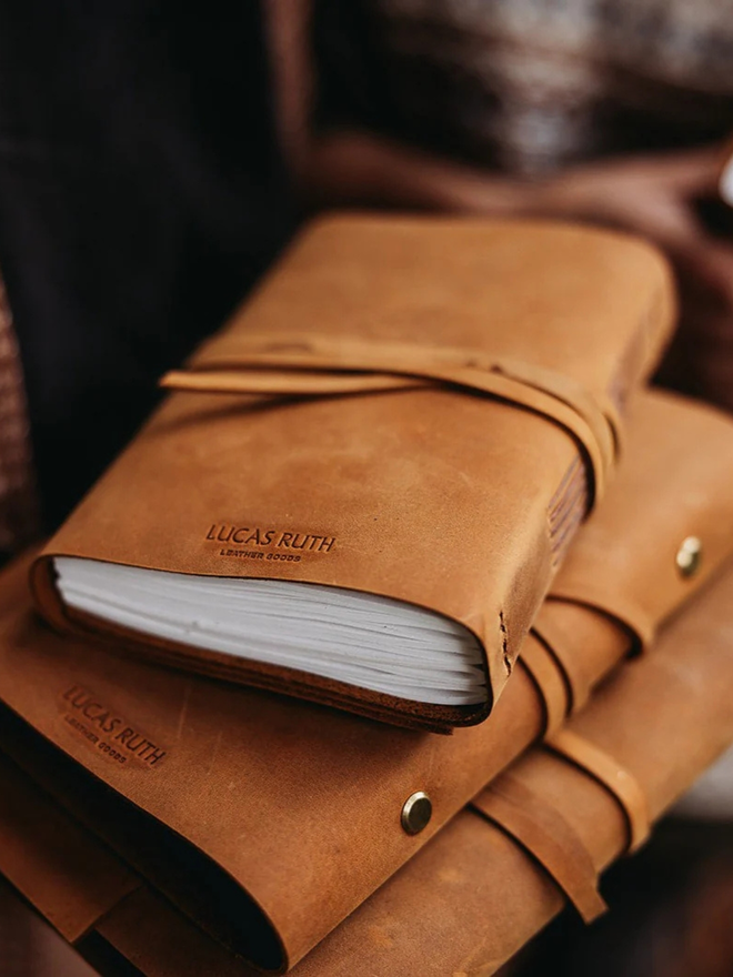 a6 leather pocket journal. a stack of light brown leather bound journals.