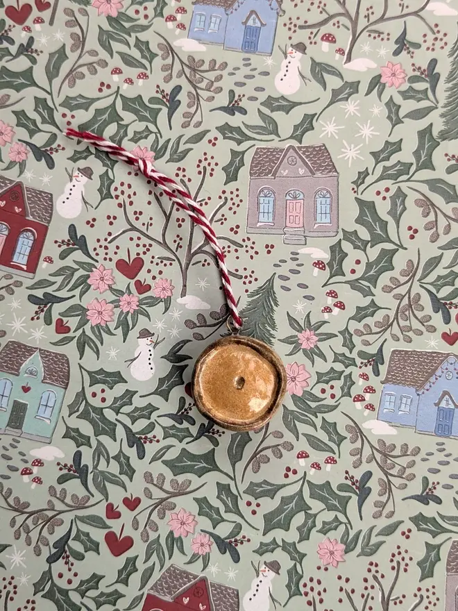 ceramic scotch pie hanging christmas decoration. a small ceramic pie decoration hanging from red and white string.