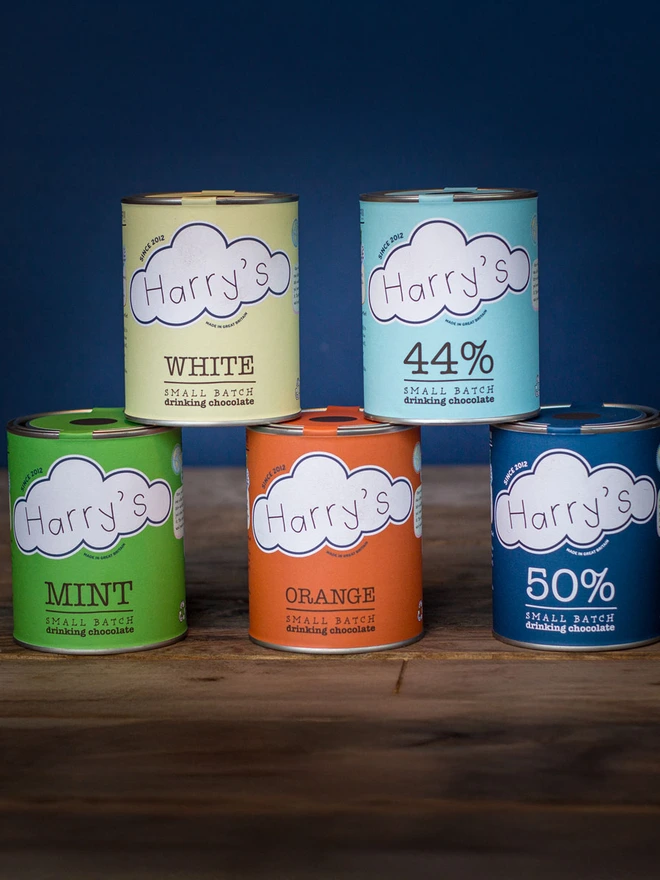Five hot chocolate tins stacked up to show what you receive in the full monty selection pack. 