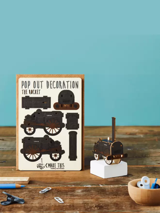 Stephenson's Rocket train decoration and train pattern greeting card and brown kraft envelope displayed on a wooden desk