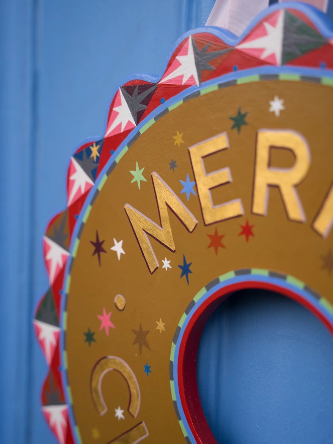 Multicoloured Hand painted Christmas Wreath with gold leaf lettering on a blue front door