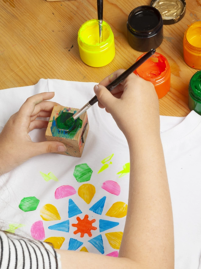 Hands shown painting stamps to print onto tshirt