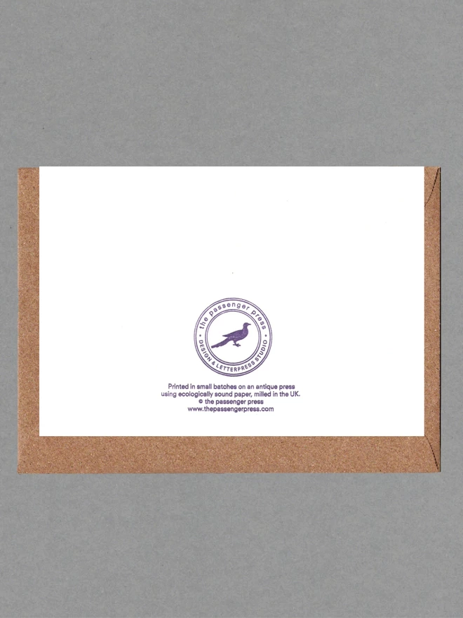 Back of white card with purple text with a brown envelope behind it