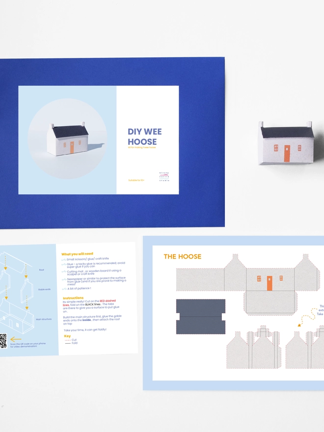 A photo of the elements of the DIY kits laid flat including - instructions, cut out sheet, a bothy made of a paper, an envelope with a label saying it is a DIY kit. 