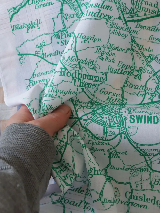 A  hand holding a Mr.PS Swindon map hankie printed in green