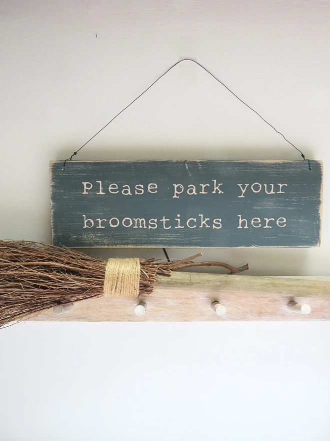 distressed hand painted wooden sign with broomstick parking message