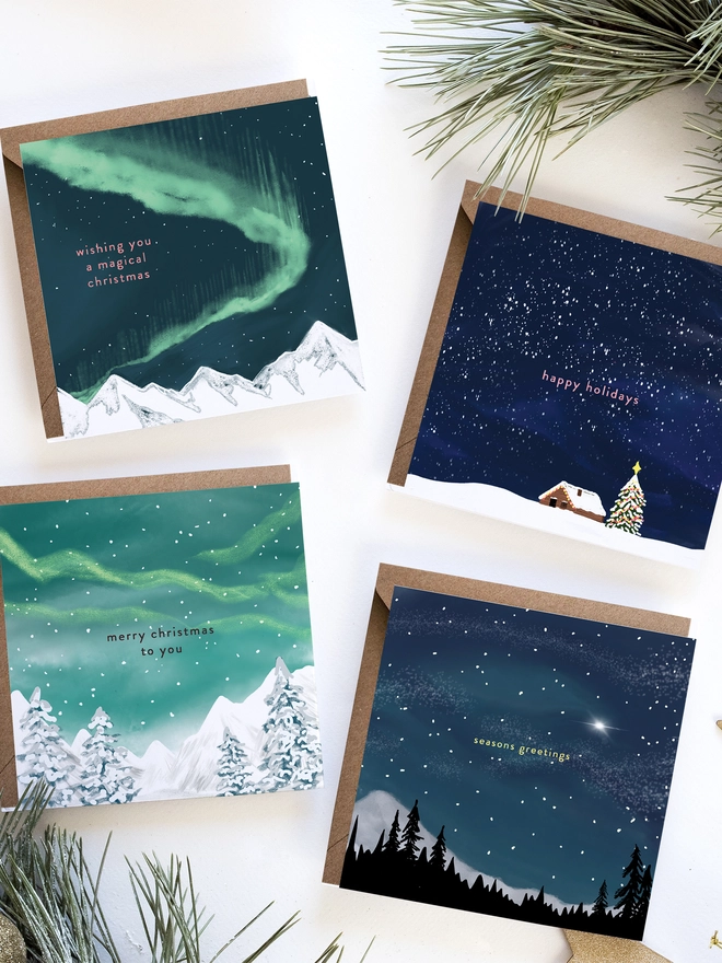 Illustrated Christmas Card Pack featuring 4 square cards. Each design shows a different view of a starry night sky 