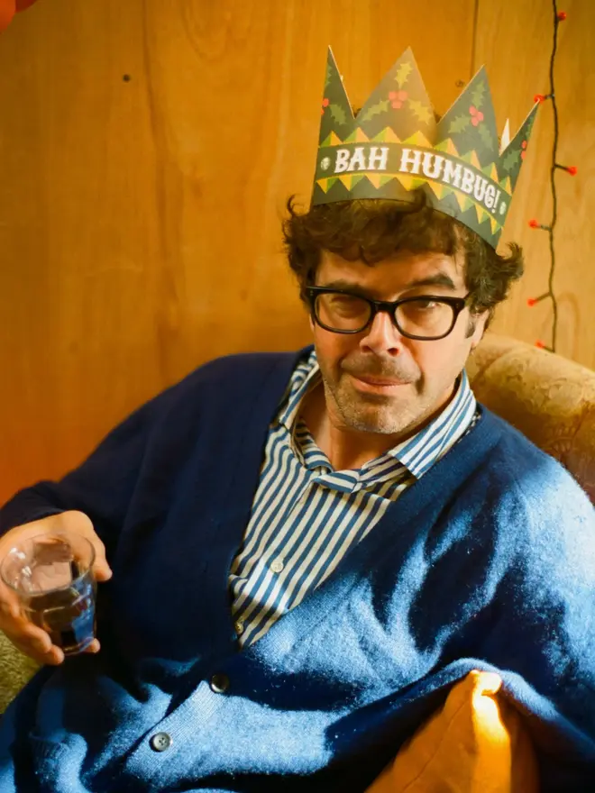 man wearinf green and red paper crown card with 'bah humbug' text