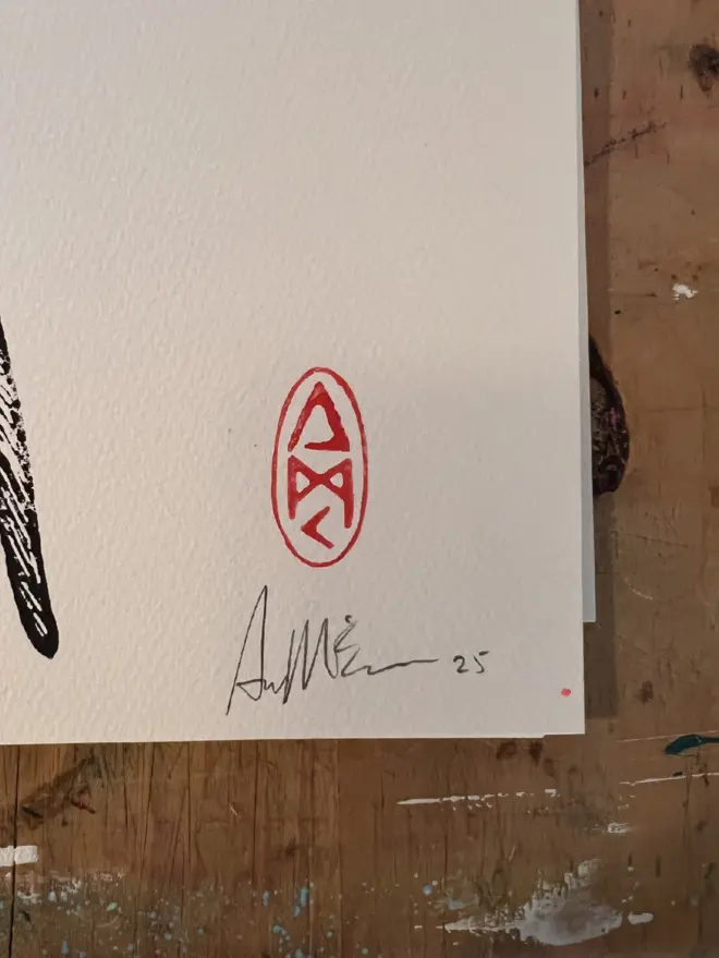 Punk budgie lino print, with symbols, coloured with blue and pink paint with on a white background. 