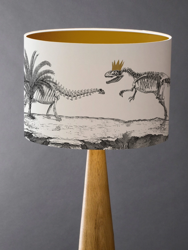 Drum Lampshade featuring Dinosaurs with a gold inner on a wooden base 