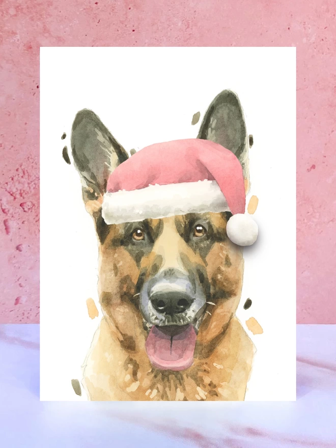 A Christmas card featuring a hand painted design of a german shepherd, stood upright on a marble surface. 
