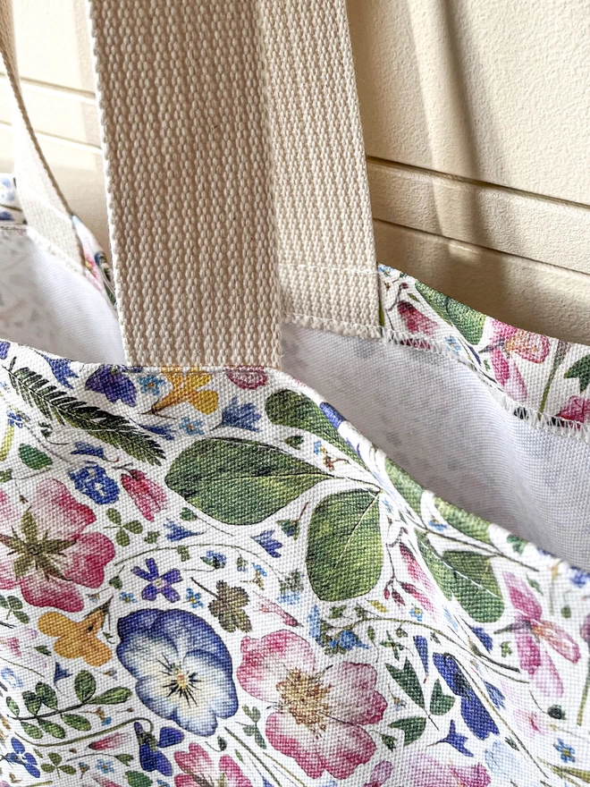 Close-up of a nature-inspired tote bag with floral design and robust webbed handles.