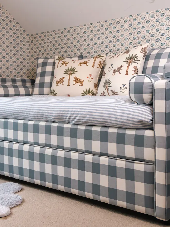 'The Posie' blue gingham upholstered children's bed. a blue gingham sofa-style bed for children featuring a duvet and cushions.