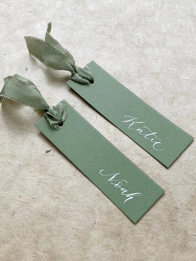 sage green calligraphy wedding place cards. green wedding place cards with silk ribbon and white calligraphy.