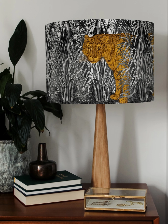 A decorative lampshade featuring an elegant tiger moving through tall tropical grasses, inspired by Henri Rousseau’s jungle paintings, with a rich botanical design.